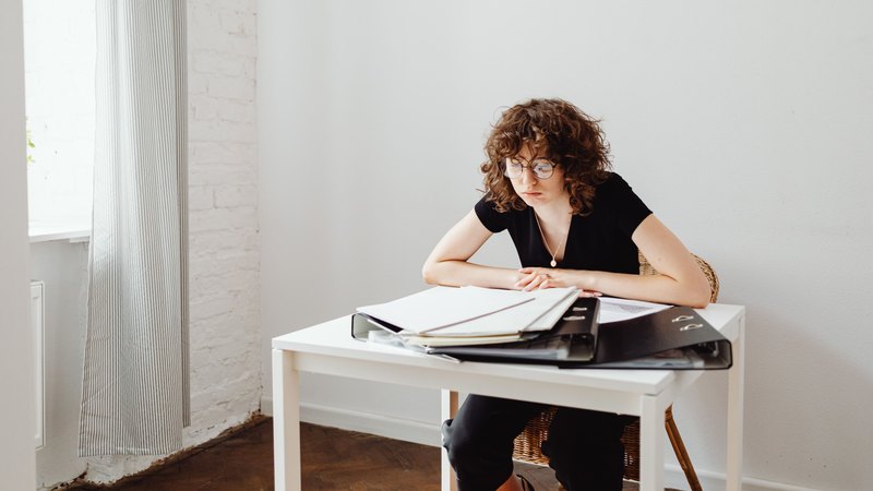 A nursery practitioner sitting at a child-height table, reading through paperwork