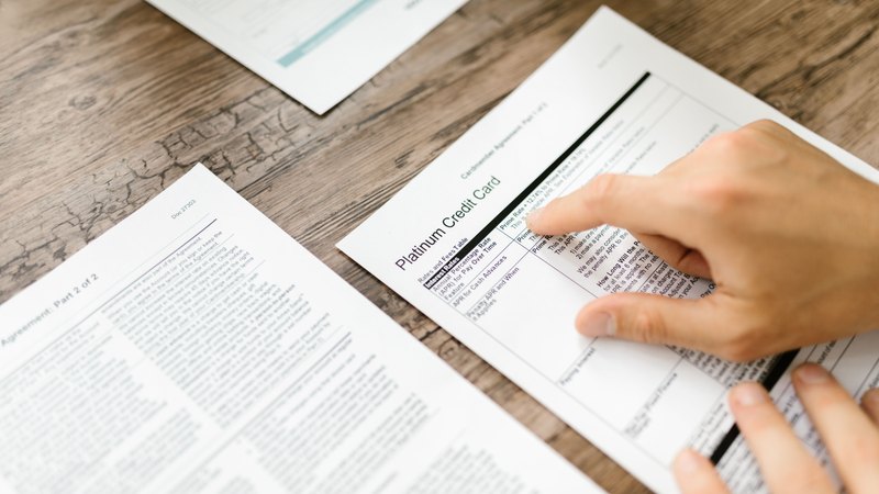 A hand pointing at a line on a printed document on a desk