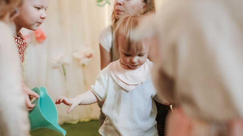 Two nursery practitioners supervising a group of toddlers playing on the floor